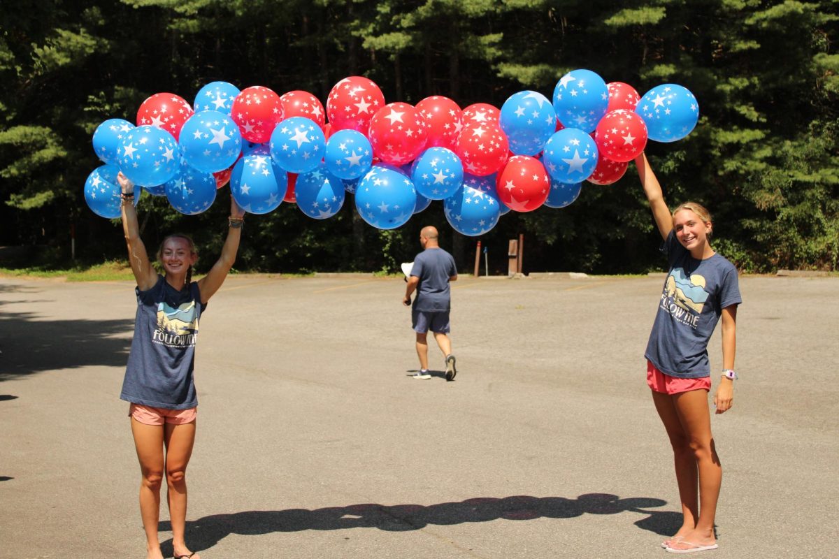 Reily Anderson and Molly Griffin hold up their balloon arch as the seniors prep for the arrival of the juniors, sophomores and freshman to Windy Gap. The senior tradition of a warm welcome created an electric atmosphere for the students. 